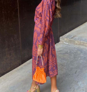 Nine-quarter sleeve V-neck painted dress by M Chic Boutique, featuring a colorful abstract pattern and flowing fit.
